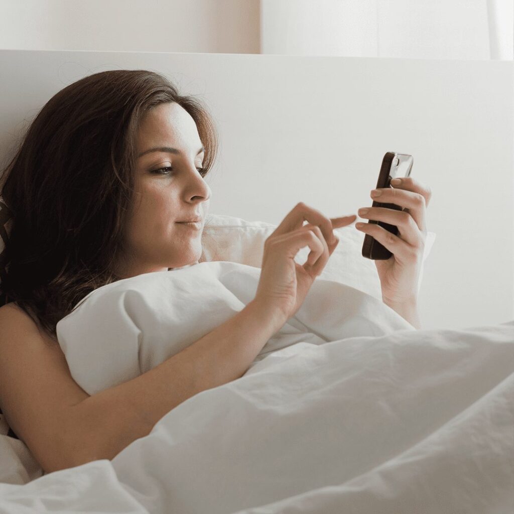 woman in bed on her phone