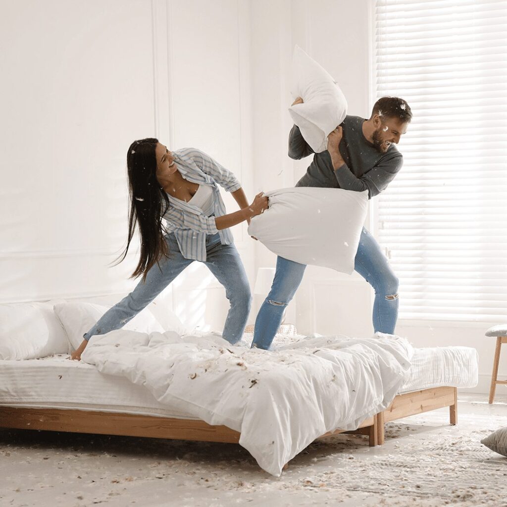 Couple pillow fighting on bed